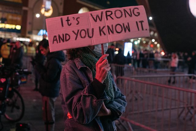 A protester holds up a sign reading "It's Wrong And You Know It" at a demonstration in Brooklyn inspired by the Kyle Rittenhouse verdict.